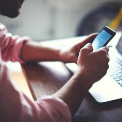 Man dials a number on his mobile from his laptop screen
